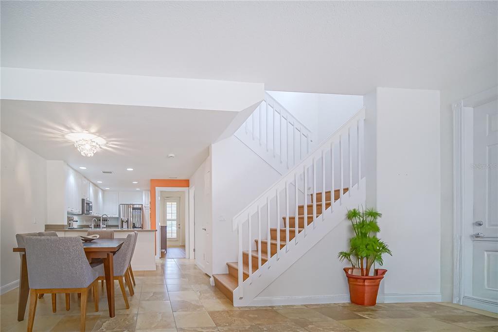 A dining area with a wooden table and chairs sits beside a white staircase — 8523 LEATHERLEAF LANE, ORLANDO, FL