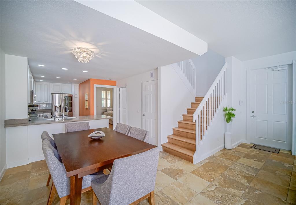 A dining area with a wooden table and chairs sits beside a staircase and kitchen — 8523 LEATHERLEAF LANE, ORLANDO, FL
