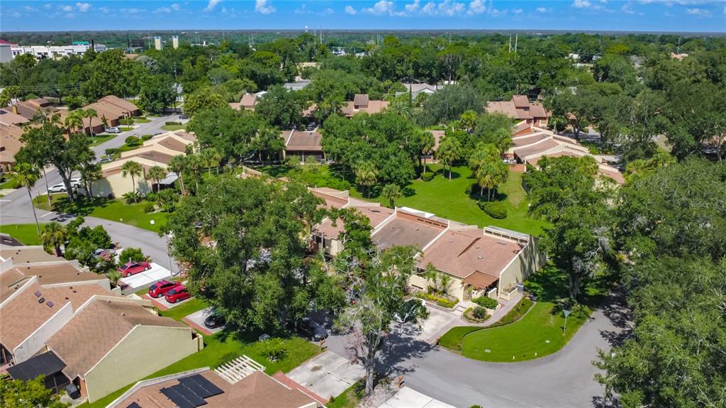 An aerial view shows a residential complex with multiple townhomes, paved driveways, and surrounding trees — 712 TEAL LANE, ALTAMONTE SPRINGS, FL