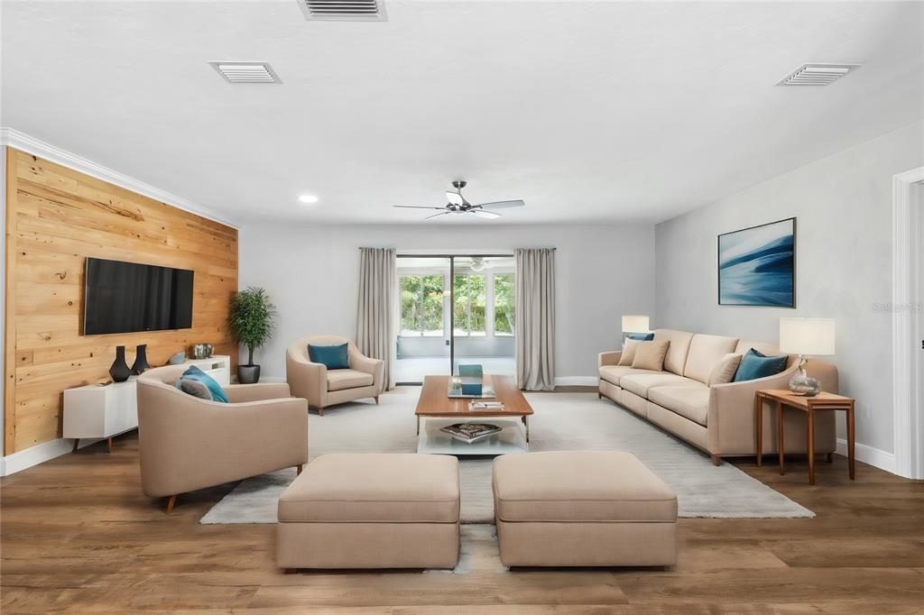 A living room features a wood-paneled accent wall, neutral furniture, and sliding glass doors — 6226 NW 53RD TERRACE, GAINESVILLE, FL