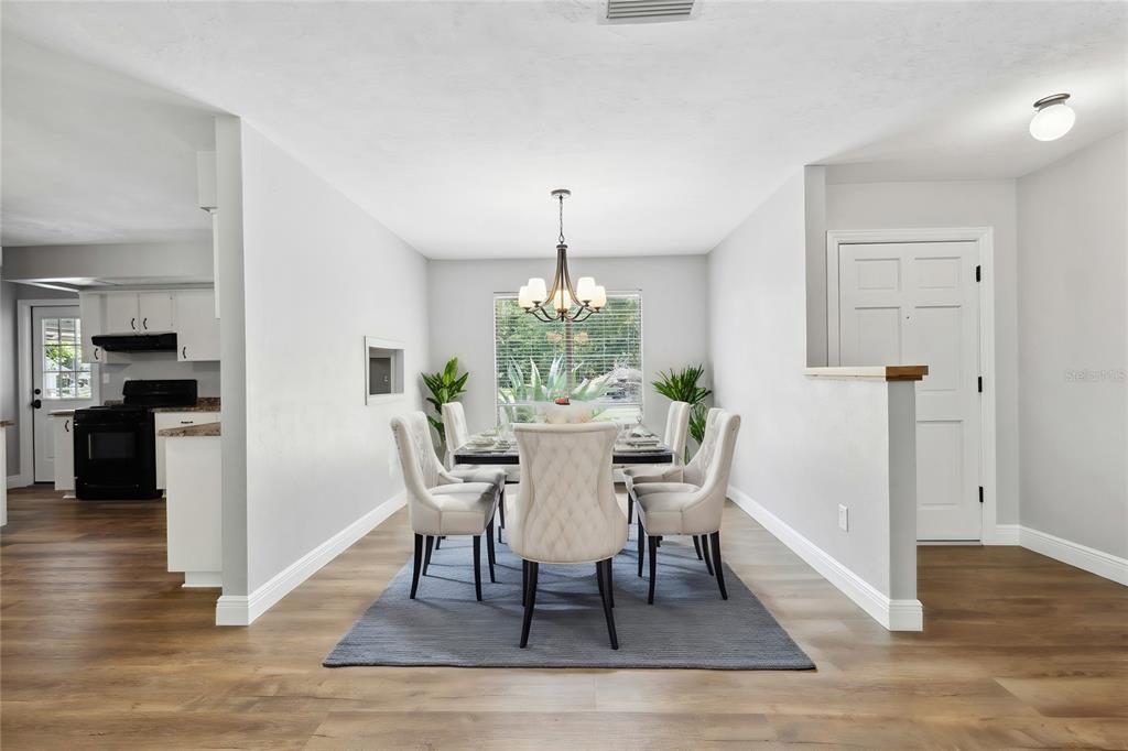 A dining room features a chandelier, a table with six chairs, and wood-look flooring — 6226 NW 53RD TERRACE, GAINESVILLE, FL