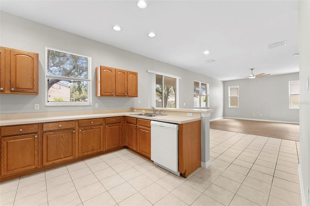 A kitchen features light-colored countertops, wood cabinets, white appliances, and tiled flooring — 10215 CYPRESS KNEE CIRCLE, ORLANDO, FL