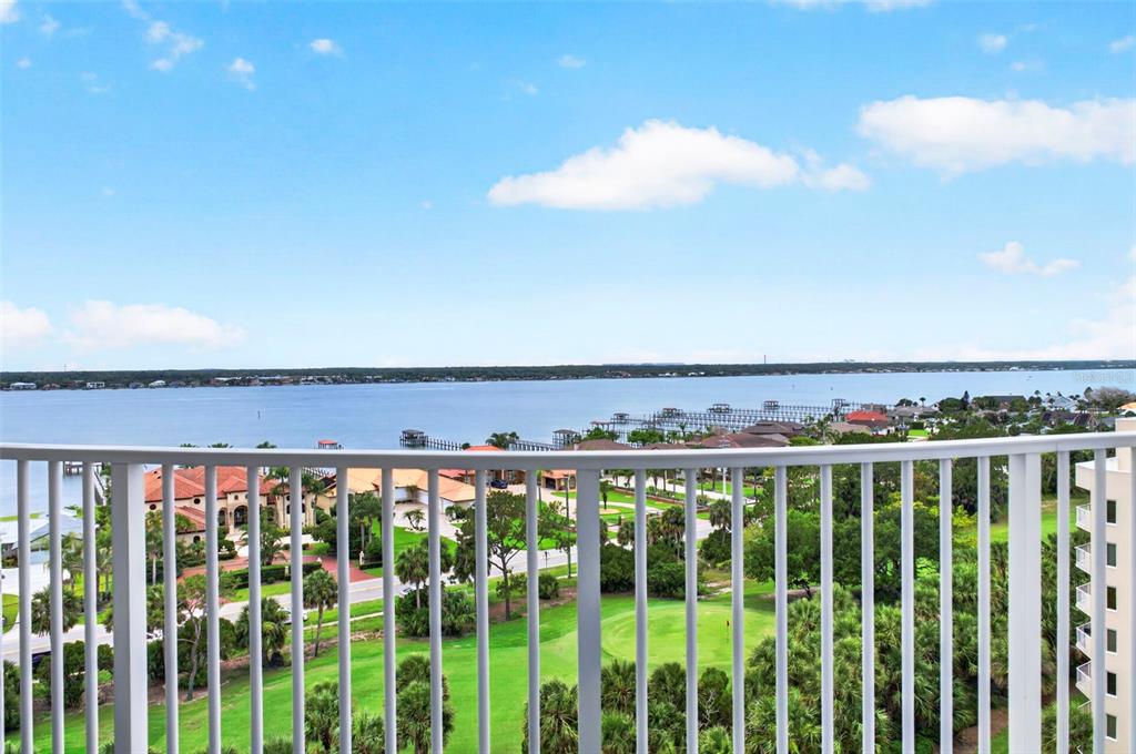 A high-angle view from a balcony overlooking a golf course, residential homes, and a bay — 2 OCEANS WEST BOULEVARD UNIT 905, DAYTONA BEACH, FL