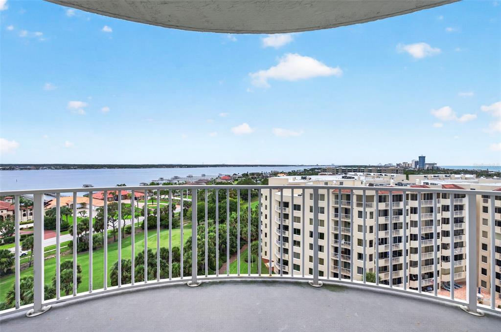 A curved balcony overlooks a golf course, a large body of water, and nearby buildings — 2 OCEANS WEST BOULEVARD UNIT 905, DAYTONA BEACH, FL