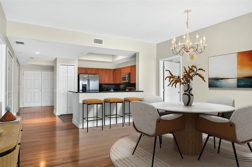 A dining area with a round table and chandelier opens to a kitchen with bar seating — 2 OCEANS WEST BOULEVARD UNIT 905, DAYTONA BEACH, FL