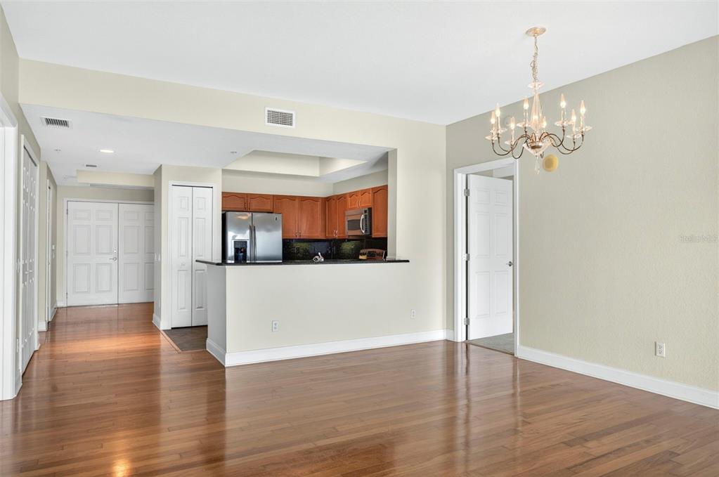 An open-concept dining area with hardwood floors leads to a kitchen with wood cabinets — 2 OCEANS WEST BOULEVARD UNIT 905, DAYTONA BEACH, FL