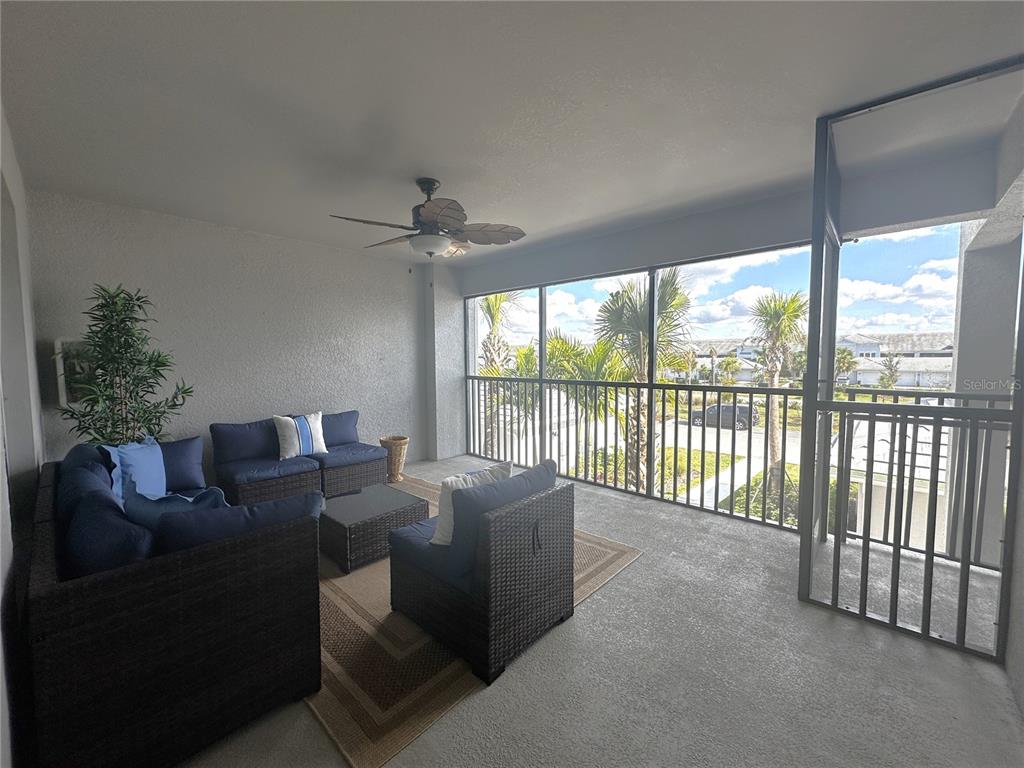 A covered balcony features dark wicker patio furniture, a ceiling fan, and a screened enclosure — 14221 HERITAGE LANDING BOULEVARD UNIT 2024, PUNTA GORDA, FL