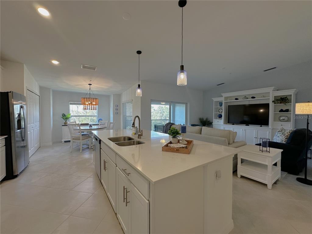 A kitchen island with a sink sits in an open-concept living and dining area — 14221 HERITAGE LANDING BOULEVARD UNIT 2024, PUNTA GORDA, FL
