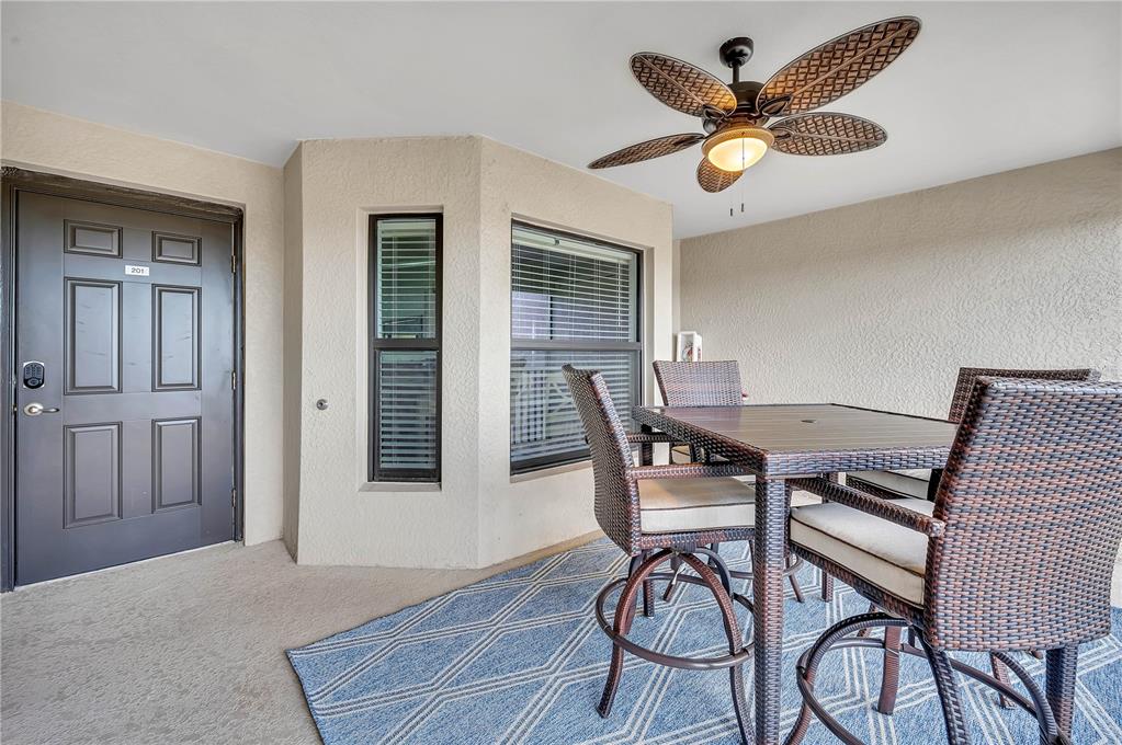 A covered patio features a dining set, a ceiling fan, and a dark entry door — 5577 PALMER CIRCLE UNIT 201, BRADENTON, FL