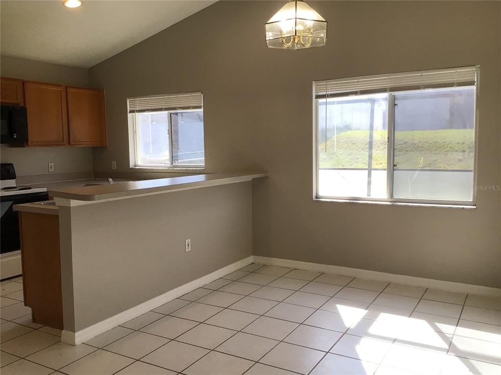 A kitchen with wood cabinets and a breakfast bar overlooks a tiled dining area — 509 HILLCREST DRIVE, DAVENPORT, FL