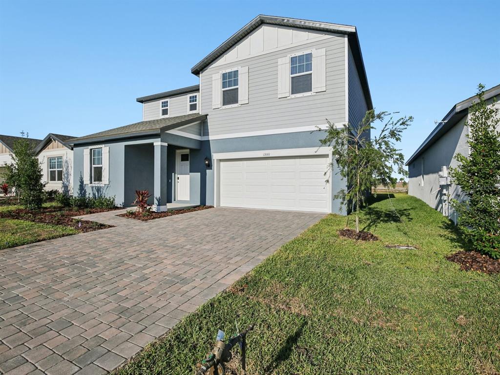 A two-story house with gray siding, a white garage door, and a paved driveway — 13311 SHELLMORE AVENUE, PALMETTO, FL