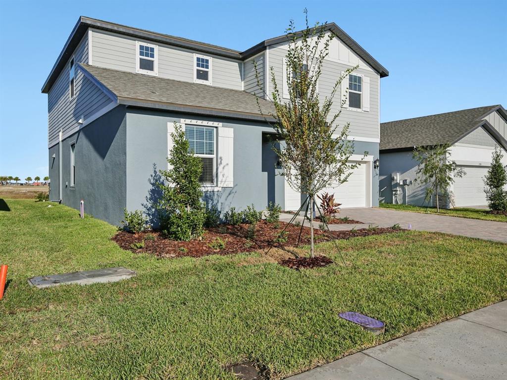 A two-story house with blue stucco and gray siding features a front yard and driveway — 13311 SHELLMORE AVENUE, PALMETTO, FL