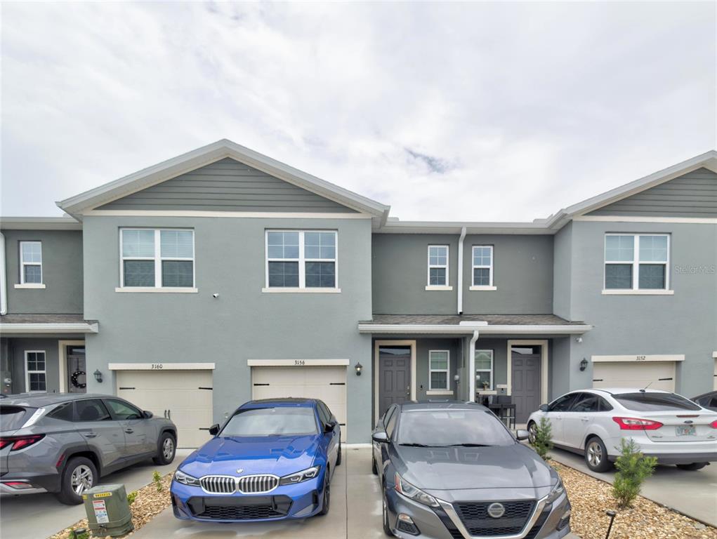 A row of two-story townhouses with gray stucco siding and attached garages — 3156 GOOSE ROAD, DAVENPORT, FL