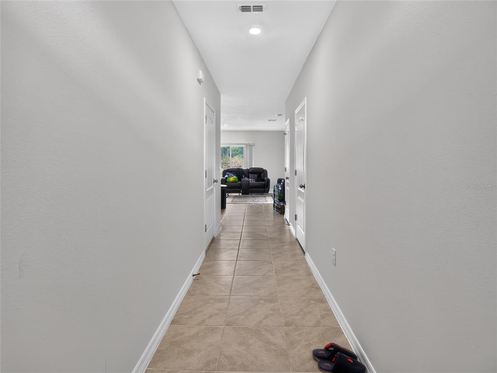 A tiled hallway leads from the foreground toward a living room with a dark sofa — 3156 GOOSE ROAD, DAVENPORT, FL