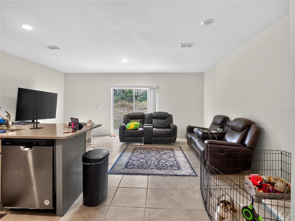 A living room with tile floors, a kitchen island, and leather furniture faces a sliding door — 3156 GOOSE ROAD, DAVENPORT, FL