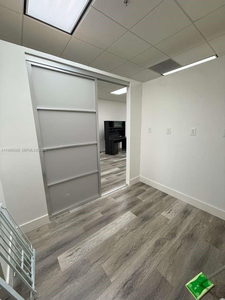 An office space features gray wood-look flooring, white walls, and a sliding glass door — 7791 NW 46th St # 201, Doral FL 33166, DORAL, FL