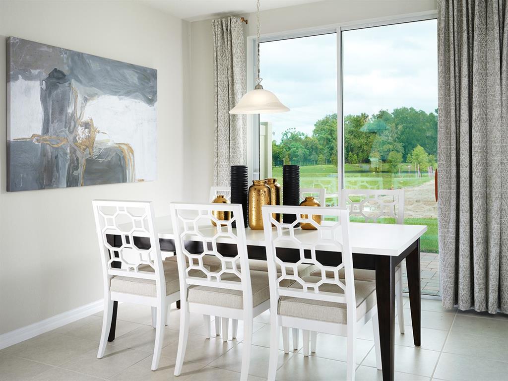 A dining room with a white table, patterned chairs, and a view of a grassy field — 4581 RANGELAND WAY, ST CLOUD, FL