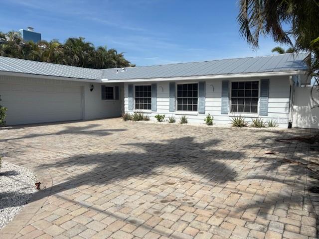A single-story house with a metal roof and a large brick-paved driveway — 12055 4TH STREET E, TREASURE ISLAND, FL