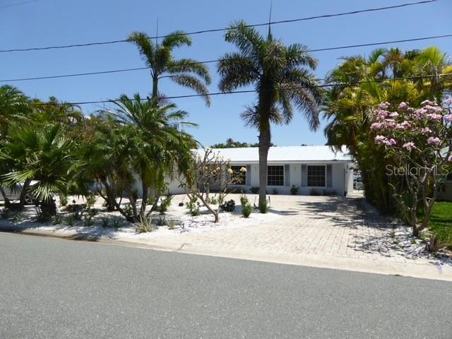 A single-story house with a paved driveway and palm trees in the front yard — 12055 4TH STREET E, TREASURE ISLAND, FL