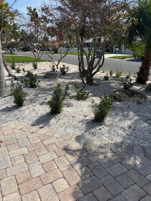 A paved driveway leads to a landscaped front yard with small shrubs and trees — 12055 4TH STREET E, TREASURE ISLAND, FL