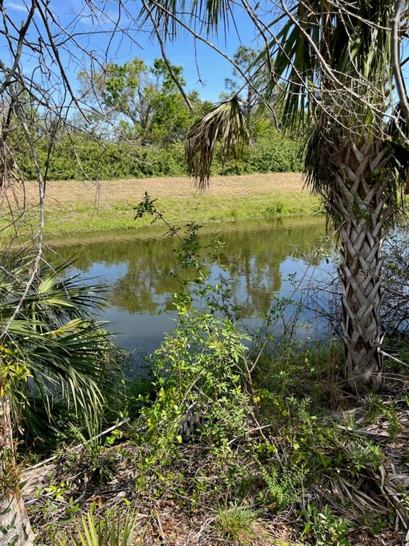 A view of a calm pond bordered by trees and vegetation under a clear blue sky — LOT 54 & 55 NEWMAN DRIVE, NORTH PORT, FL