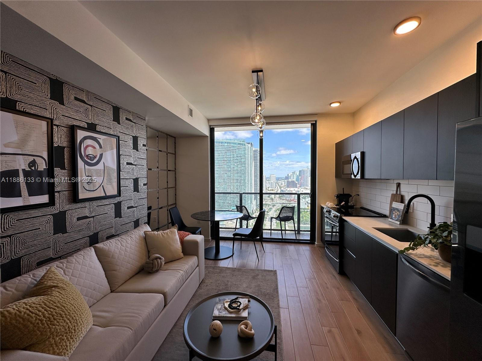 A modern studio apartment features a kitchen, living area, and balcony with city views — 398 NE 5th St # 3008, Miami FL 33132, MIAMI, FL