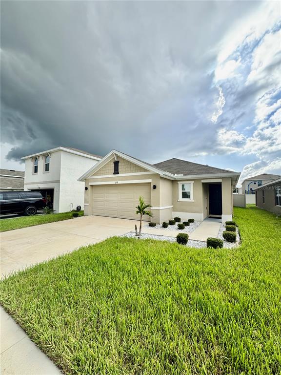 A single-story suburban house with a tan exterior, two-car garage, and a green lawn — 12176 WATER ASH PLACE, RIVERVIEW, FL