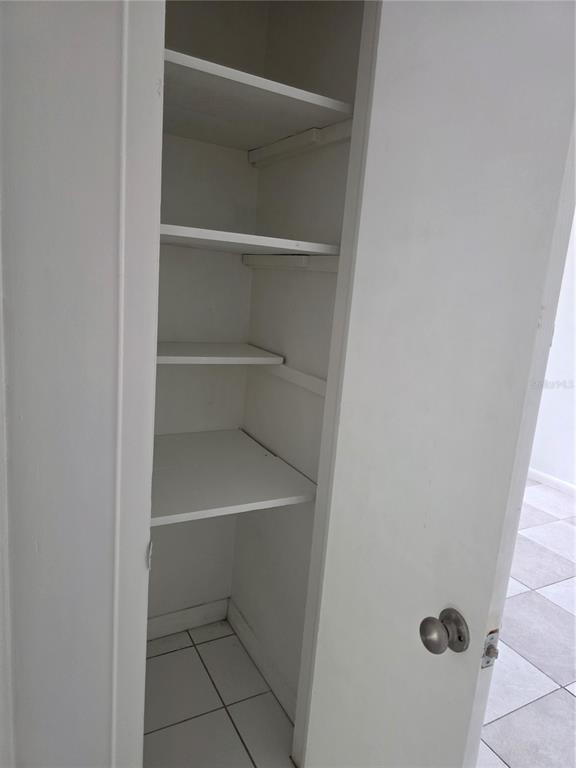 A white closet with four interior shelves and a round metal doorknob — 1212 E CHILKOOT AVENUE, TAMPA, FL