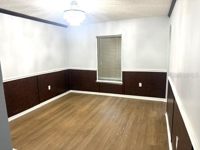 A room features light wood-look flooring, white upper walls, dark wainscoting, and a window with blinds — 409 YEARLING COVE LOOP, APOPKA, FL