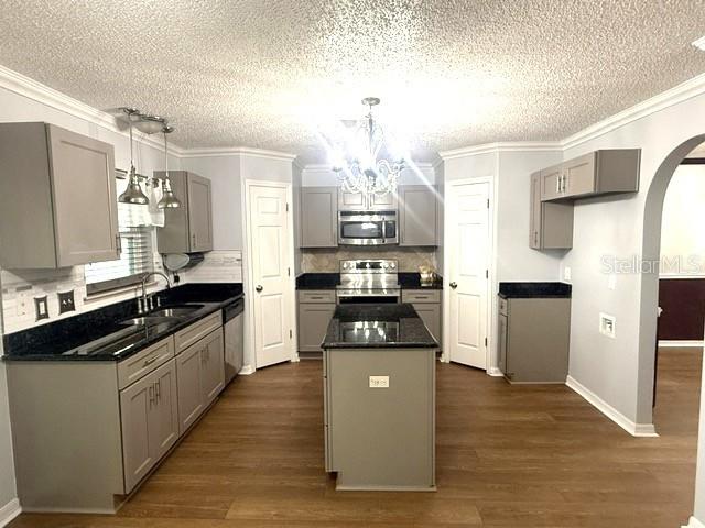 A kitchen features gray cabinets, dark countertops, a center island, and light wood-look flooring — 409 YEARLING COVE LOOP, APOPKA, FL