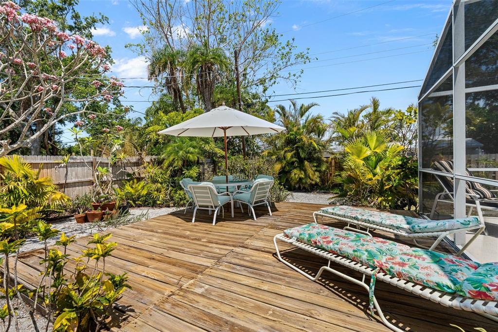 A wooden deck features a dining set with an umbrella and two lounge chairs outdoors — 139 ADAIR AVENUE, SARASOTA, FL
