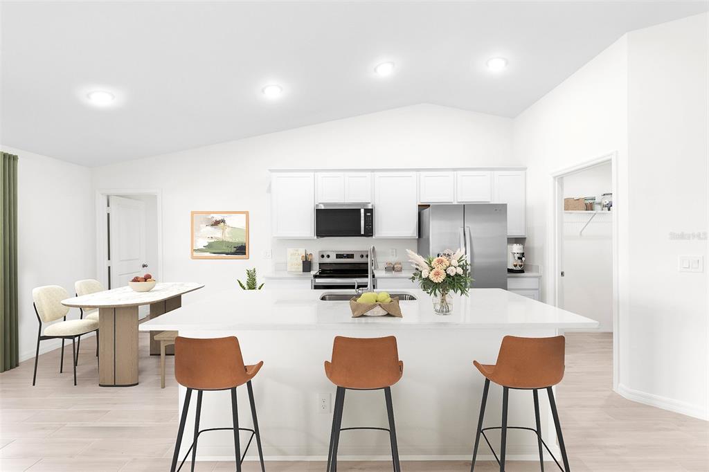 A modern kitchen features a large white island with bar stools and white cabinetry — 7338 PRINTER STREET, PORT CHARLOTTE, FL