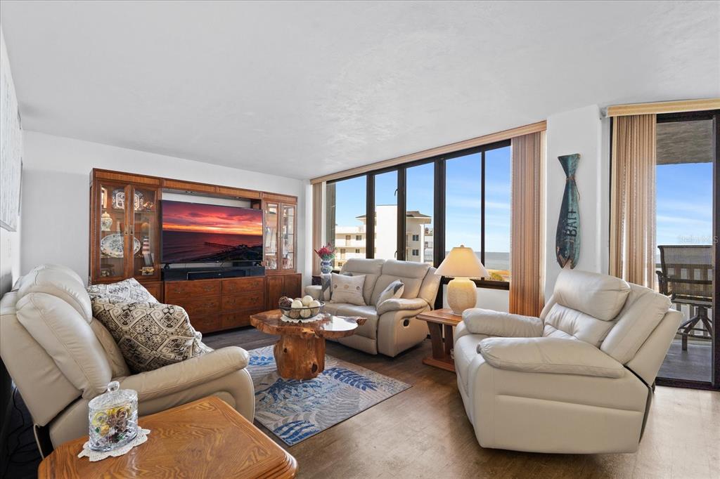 A living room with light leather furniture, a wooden coffee table, and large ocean-view windows — 3580 S OCEAN SHORE BOULEVARD UNIT 204, FLAGLER BEACH, FL