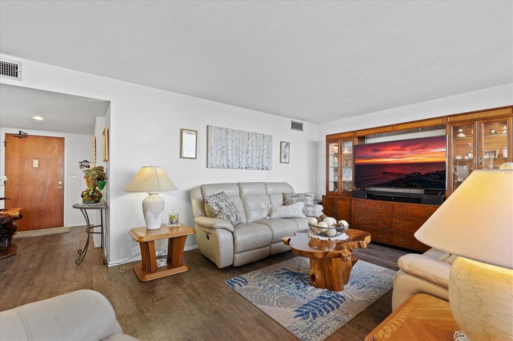 A living room features a light-colored sofa, a wooden coffee table, and a large entertainment center — 3580 S OCEAN SHORE BOULEVARD UNIT 204, FLAGLER BEACH, FL