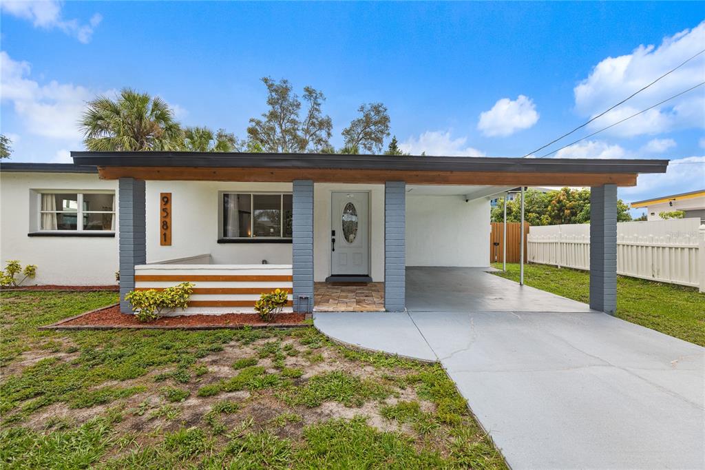 A single-story house features a flat roof, a carport, and a small front porch area — 9581 49TH WAY N, PINELLAS PARK, FL