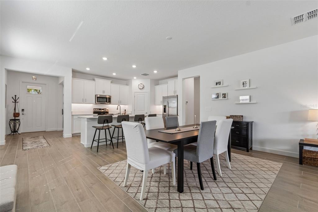 An open-concept kitchen and dining area features white cabinetry, a kitchen island, and wood-look flooring — 31735 GRIFFIN SANDS LANE, SAN ANTONIO, FL