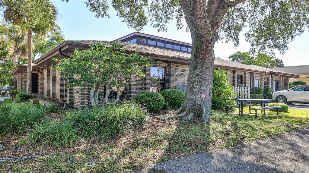 A single-story brick office building features a clerestory roof, mature trees, and a picnic table — 4 OLD KINGS ROAD N UNIT 2A, PALM COAST, FL