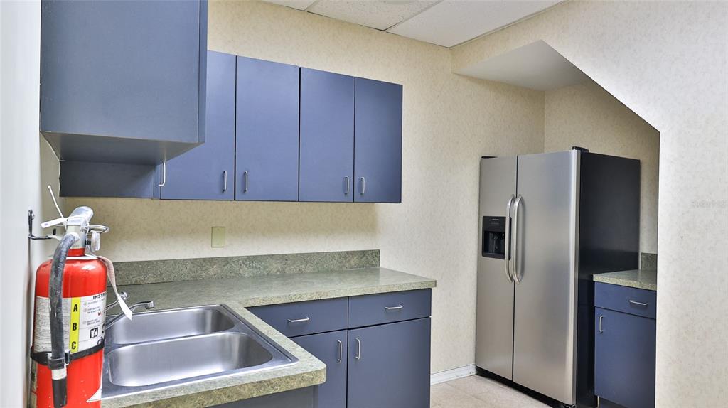 A kitchen features blue cabinets, a stainless steel refrigerator, and a double basin sink — 4 OLD KINGS ROAD N UNIT 2A, PALM COAST, FL