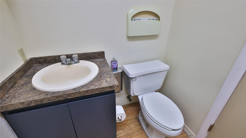 A small bathroom features a vanity with a dark cabinet, a toilet, and a paper dispenser — 4 OLD KINGS ROAD N UNIT 2A, PALM COAST, FL
