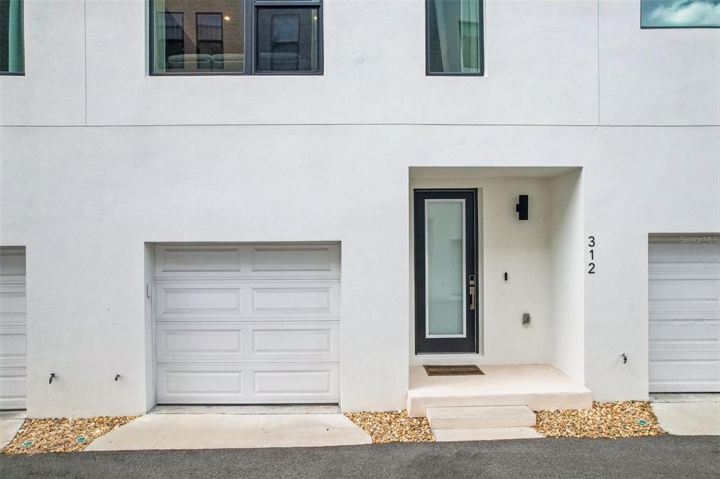 The exterior of a modern white townhouse features a garage, a front door, and gravel — 312 15TH STREET N, ST PETERSBURG, FL