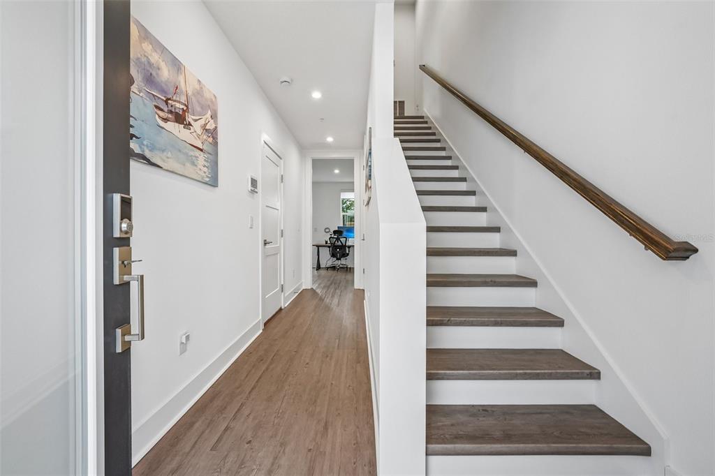 A hallway features wood-look flooring, a staircase with a wooden handrail, and a distant office — 312 15TH STREET N, ST PETERSBURG, FL