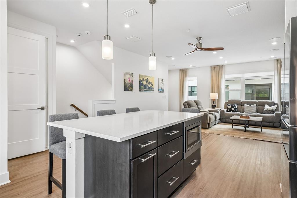 A kitchen island with dark cabinets and a white countertop sits before an open living area — 312 15TH STREET N, ST PETERSBURG, FL