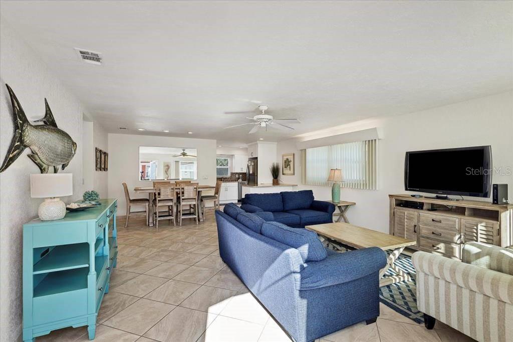 A living room and dining area feature tile flooring, blue sofas, and a large fish wall decoration — 6154 MIDNIGHT PASS ROAD UNIT A18, SARASOTA, FL
