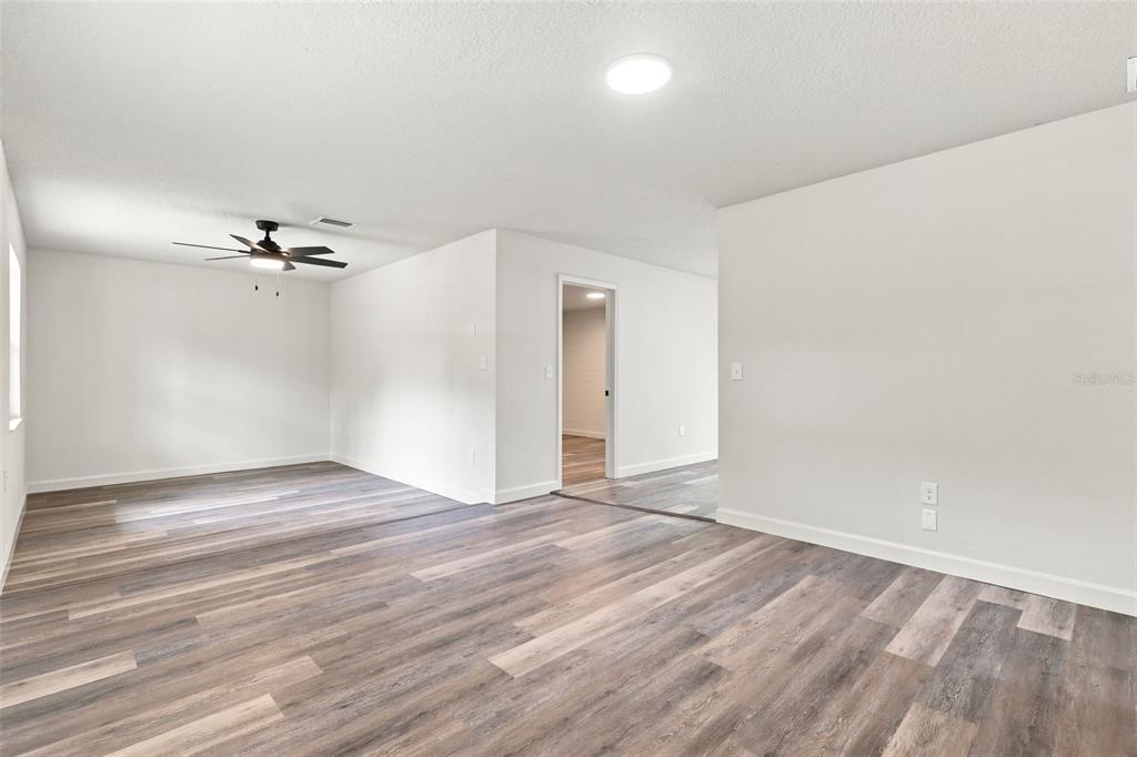 An empty room with wood-look flooring, white walls, and a ceiling fan — 6204 ASHLAND AVENUE, LEESBURG, FL