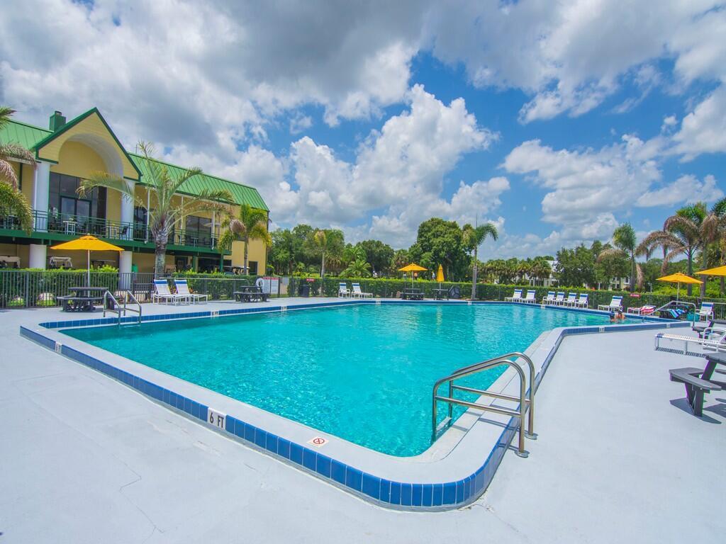 A large outdoor swimming pool sits in front of a yellow building with a green roof — 4210 Gator Trace Avenue # B, Fort Pierce FL 34982, FORT PIERCE, FL