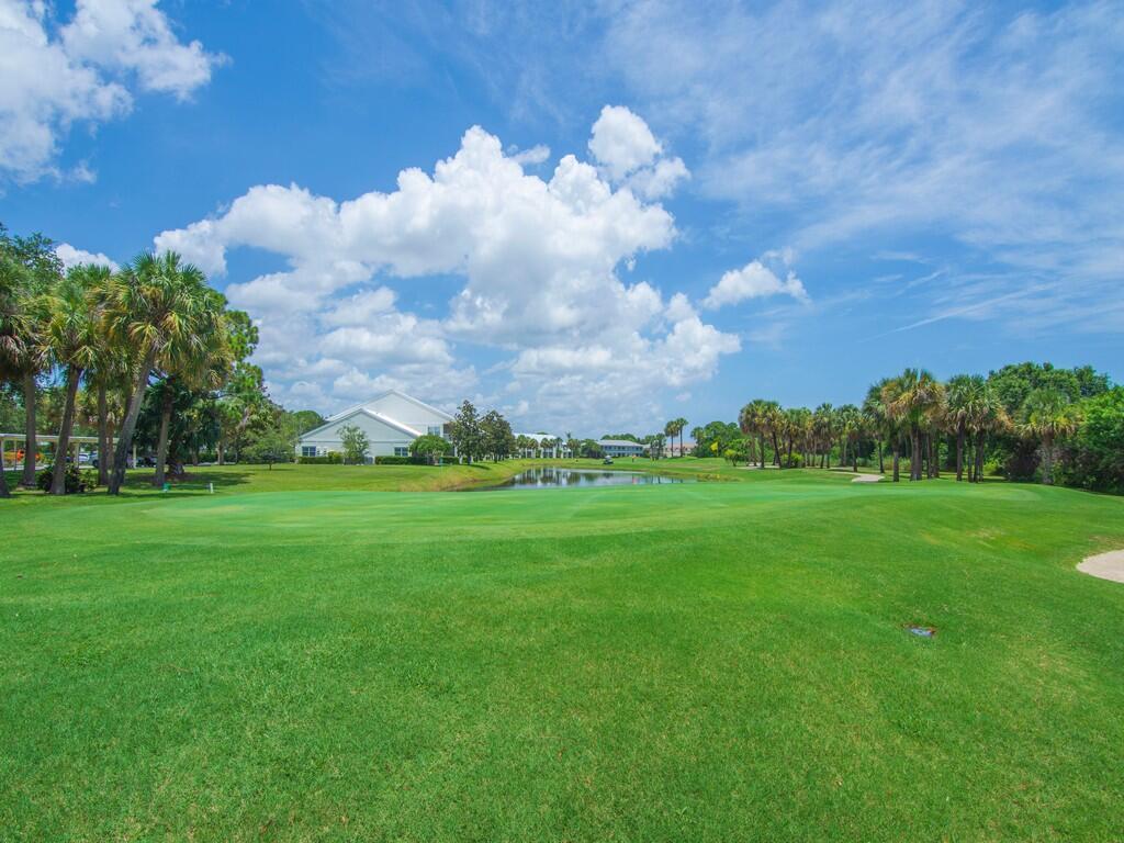 A view of a golf course green with a pond, palm trees, and buildings beyond — 4210 Gator Trace Avenue # B, Fort Pierce FL 34982, FORT PIERCE, FL