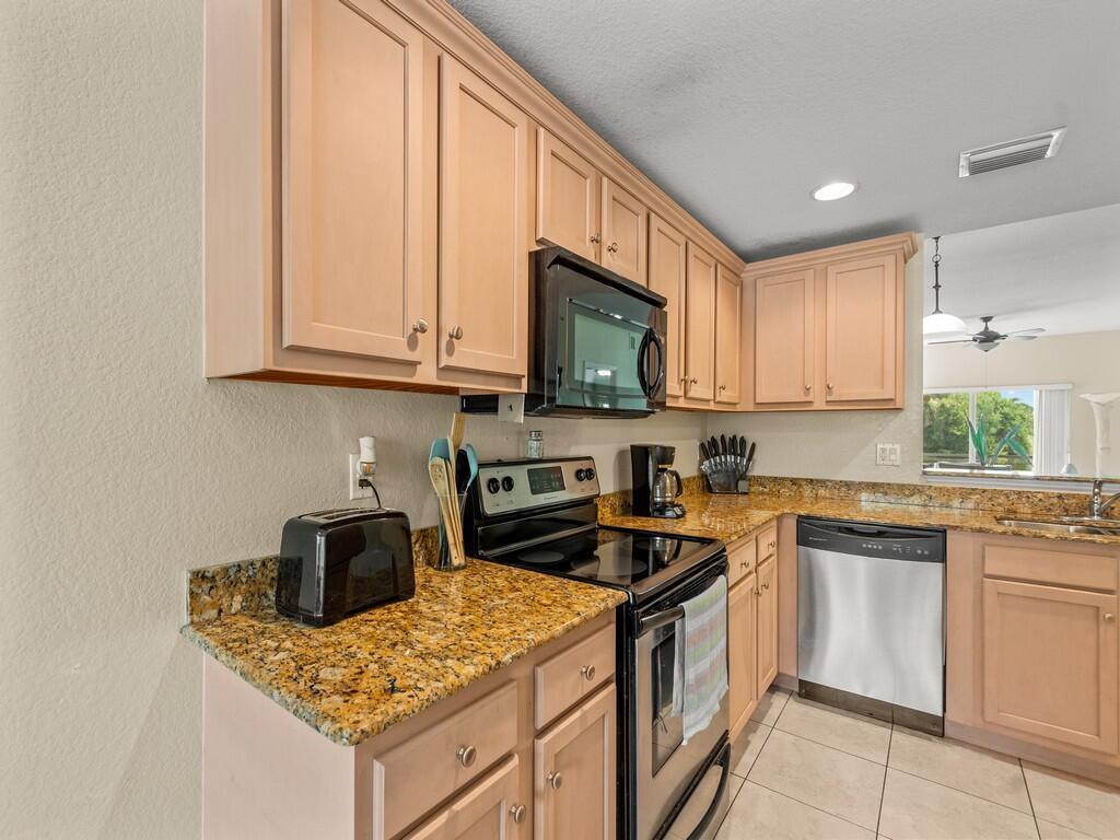 A kitchen features light wood cabinets, granite countertops, stainless steel appliances, and tile flooring — 4210 Gator Trace Avenue # B, Fort Pierce FL 34982, FORT PIERCE, FL