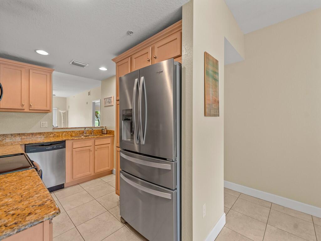 A kitchen with light wood cabinets, granite countertops, stainless steel appliances, and tile flooring — 4210 Gator Trace Avenue # B, Fort Pierce FL 34982, FORT PIERCE, FL
