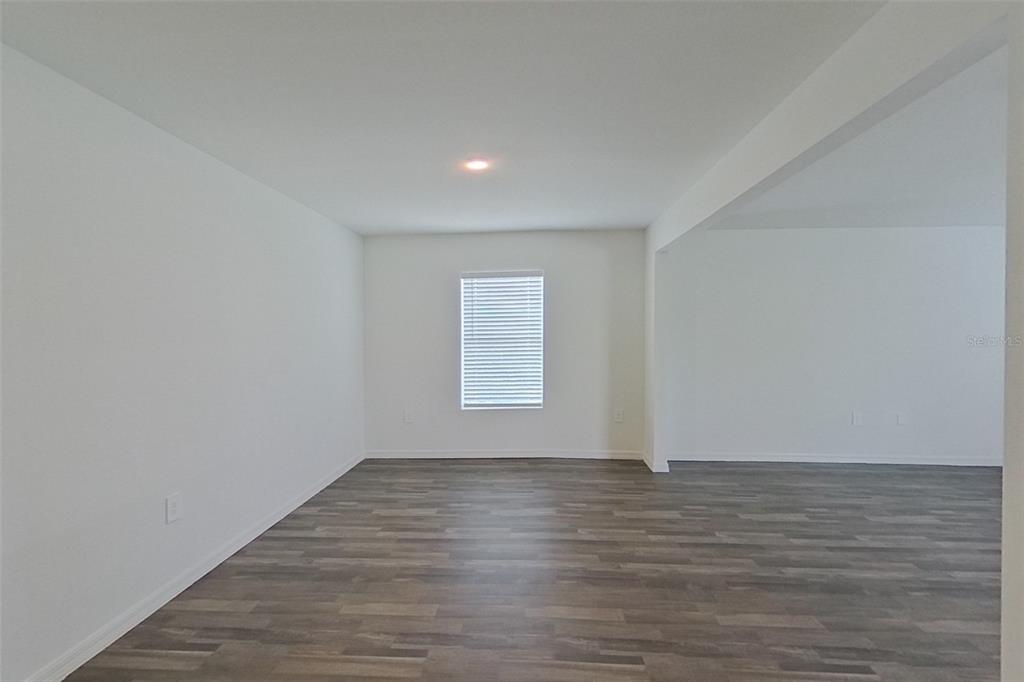 An empty room features white walls, a single window with blinds, and wood-look flooring — 4020 GARDEN BOULEVARD, CAPE CORAL, FL