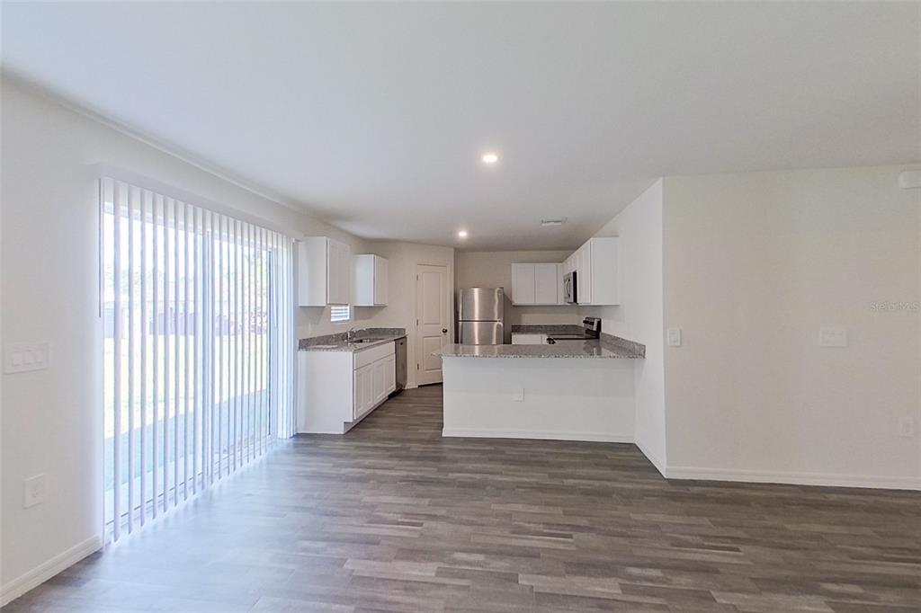 A kitchen with white cabinets and granite countertops opens to a living area with flooring — 4020 GARDEN BOULEVARD, CAPE CORAL, FL